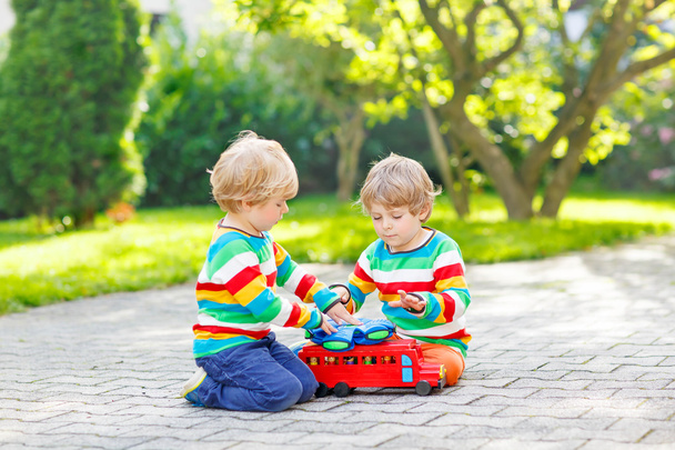 Two siblings, kid boys playing with red wooden toy - Fotografie, Obrázek