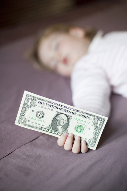 банкнота долара в руці дитини, що спить
 - Фото, зображення