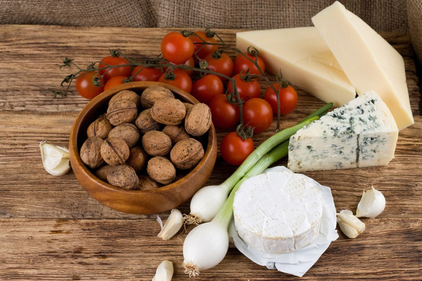 Trois sortes de fromage et divers légumes sur planche de bois
 - Photo, image