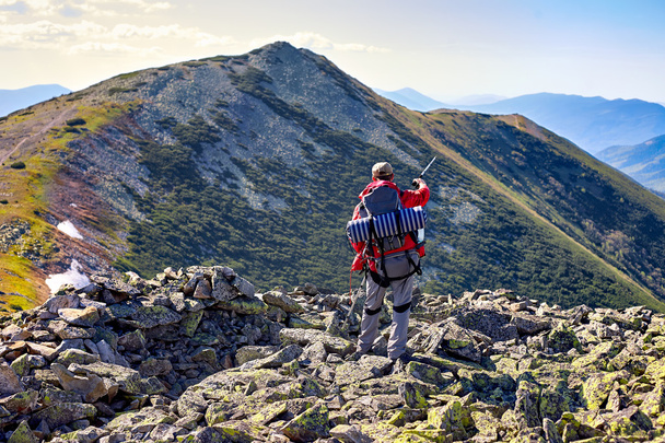 Hiker with backpack standing in the mountains and enjoying the v - Photo, Image