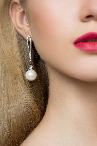 girl ear in jewelry earrings close up - Foto, afbeelding