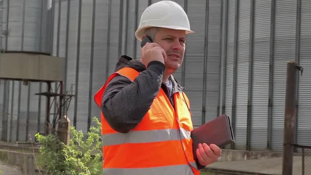 Engineer talking on cell phone at the factory - Materiał filmowy, wideo