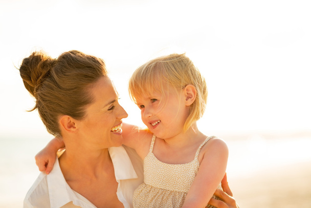 Portrait of happy mother and baby girl on beach at the evening - Photo, Image