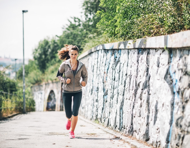 Full length portrait of fitness young woman jogging in the city  - 写真・画像
