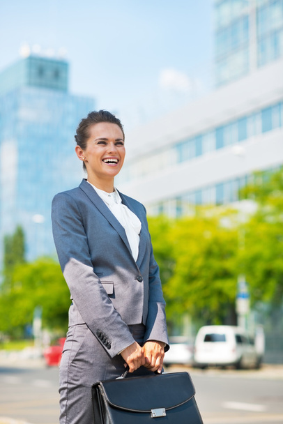 Happy business woman with briefcase in office district - Фото, изображение