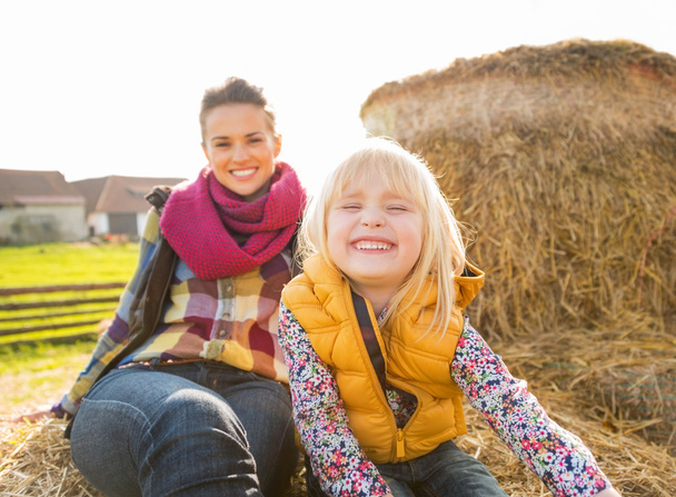 Portrait of smiling mother and child sitting on haystack - Photo, Image