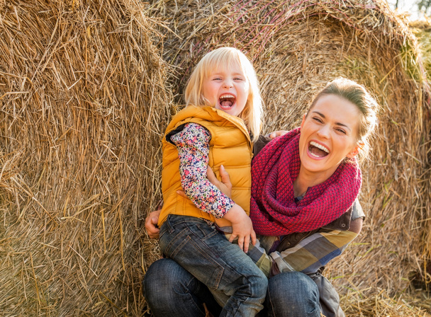 Portrait of smiling mother and child near haystack - Valokuva, kuva