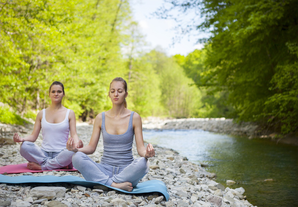 Deux femmes pratiquent le yoga près de la rivière de montagne
 - Photo, image