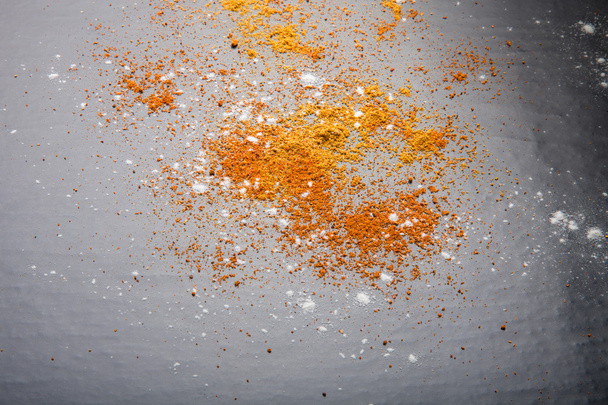 Red and yellow spices and flour on a black background. Selective - Photo, Image