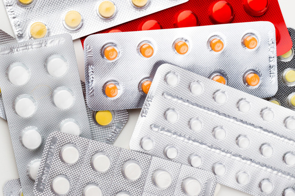Tabletten auf weißem Hintergrund in weiß, gelb, orange, eine Spritze - Foto, Bild