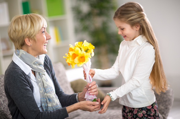  girl giving a bunch of flowers to her grandmother - Foto, Imagem