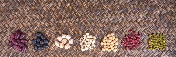 blauw oog erwten, mung bean, adzuki bonen, sojabonen, zwarte bonen en rode kidney bonen op rieten dienblad - Foto, afbeelding