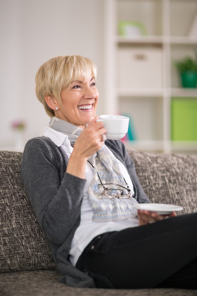 Senior woman smiling and drinking tea - Photo, Image