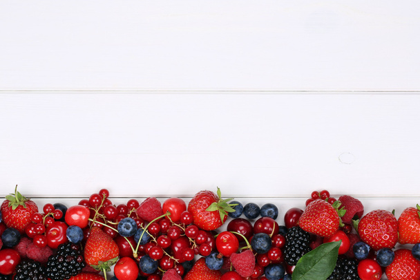 bessen vruchten op een houten bord met aardbeien, bosbessen, che - Foto, afbeelding