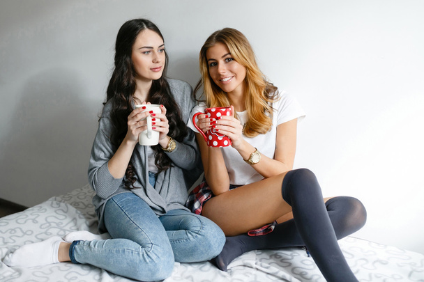 Two young beautiful girls laughing and posing with cups and inha - Foto, Imagem