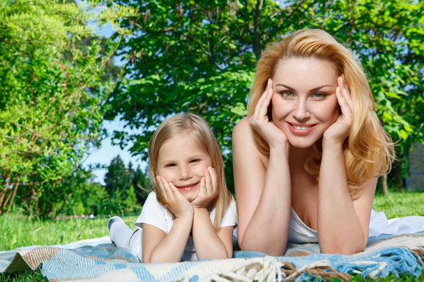 Mother and daughter lying on cover during picnic  - Zdjęcie, obraz