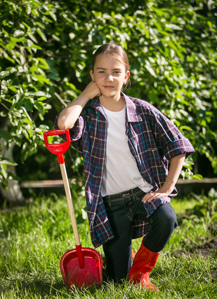 девушка в резиновых сапогах позирует с игрушечной лопатой в саду
 - Фото, изображение