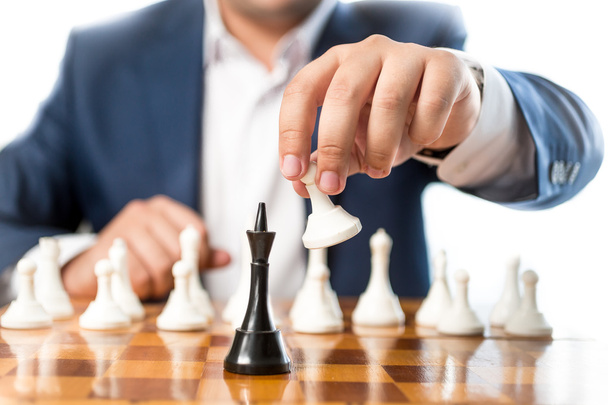 Closeup of businessman playing chess and beating black king - Photo, Image