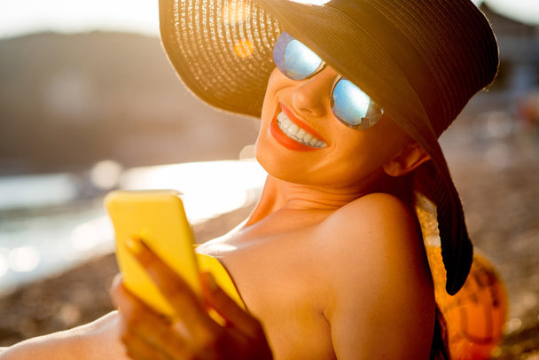 Femme utilisant un téléphone portable sur la plage
 - Photo, image
