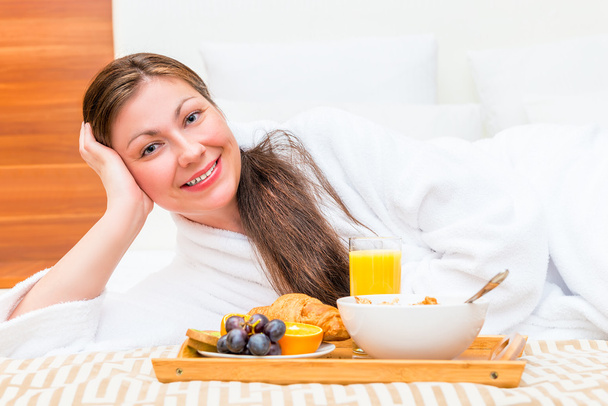 glücklich schönes Mädchen auf dem Bett mit einem Tablett mit Lebensmitteln - Foto, Bild