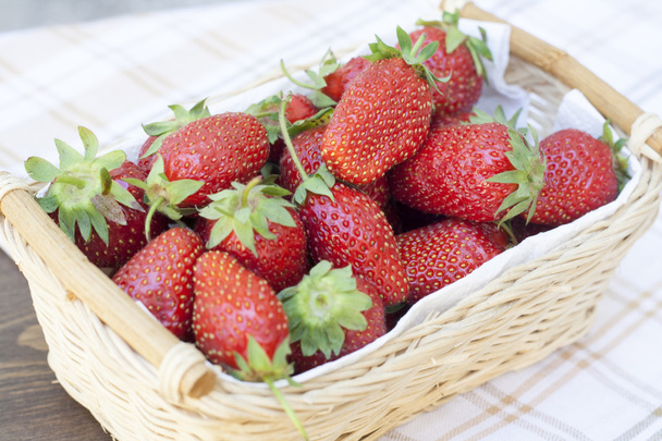 frische Erdbeeren mit grünen Schwänzen Weidenkorb mit weißer Serviette - Foto, Bild