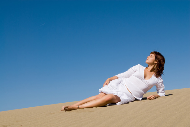 Beautiful woman lying in the sand with a white dress - Zdjęcie, obraz