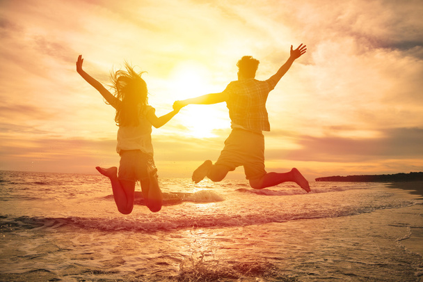 молода щаслива пара стрибає на пляжі
  - Фото, зображення