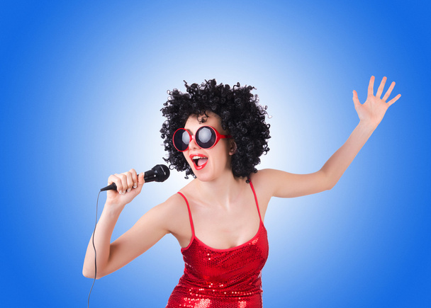 Поп-зірка з мікрофоном у червоній сукні проти градієнта
  - Фото, зображення