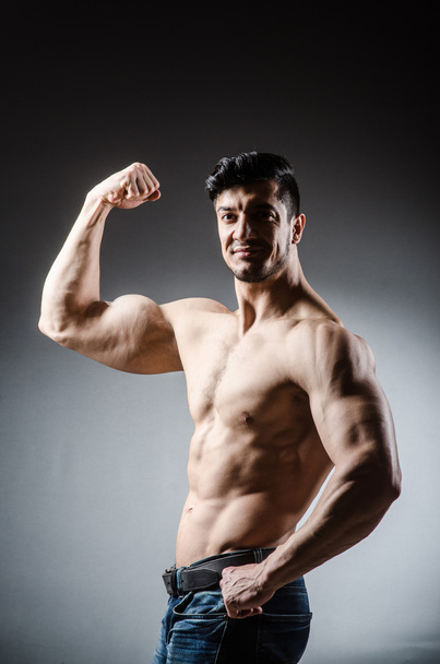 Muscular man posing in dark studio - Valokuva, kuva