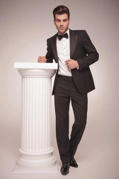элегантный бизнесмен, опирающийся на белую колонну
 - Фото, изображение