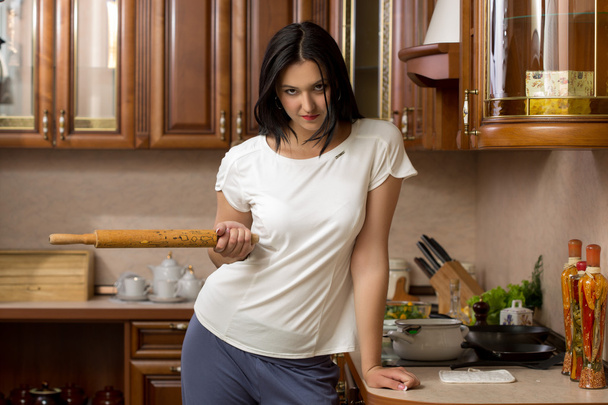 housewife holding a rolling pin. It stands in the kitchen - Foto, Imagen