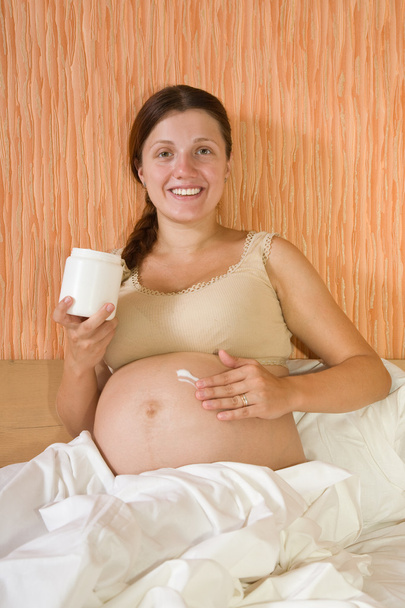 Pregnant woman rubs cream - 写真・画像