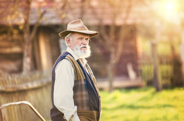 Old farmer with pitchfork taking a break - Foto, afbeelding