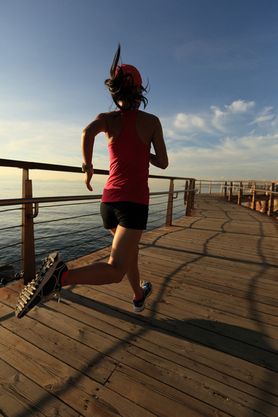 sporty female running on boardwalk - Photo, Image
