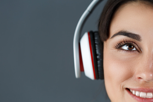 Beautiful dark haired smiling woman wearing headphones - Photo, image
