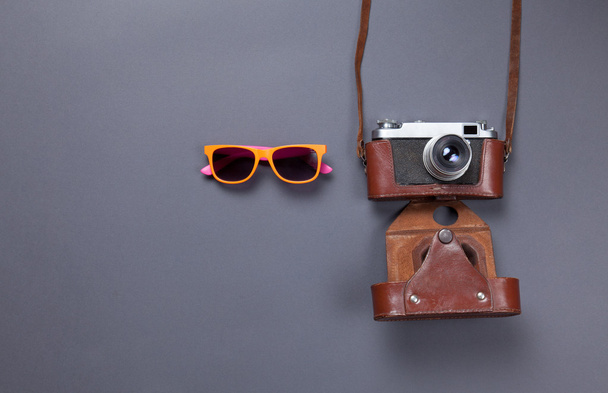 Πορτοκαλί γυαλιά ηλίου και κάμερας ρετρό σε γκρι φόντο - Φωτογραφία, εικόνα