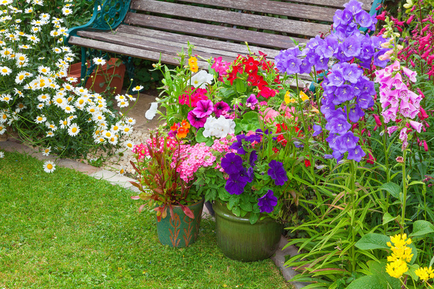 Cottage tuin met Bank en containers vol met bloemen - Foto, afbeelding