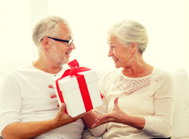 happy senior couple with gift box at home - Foto, afbeelding