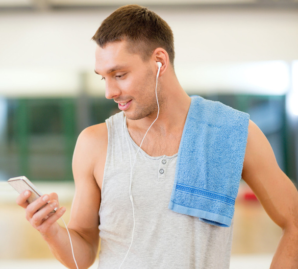 young man with smartphone and towel in gym - Φωτογραφία, εικόνα