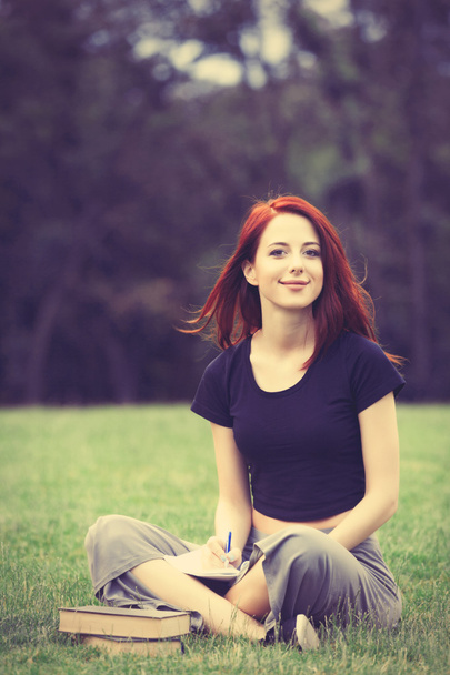 Redhaired Woman sitting studying on meadow - Foto, Imagen