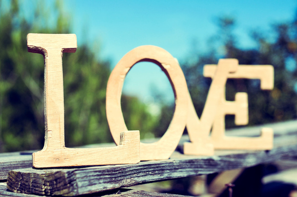деревянные буквы, образующие слово любовь в деревенском пейзаже
 - Фото, изображение