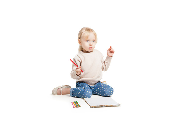 Little cute girl sitting on floor and drawing with colourful pencils - Foto, Imagem