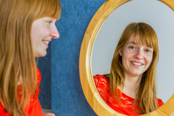 Portrait of redhead girl looking in mirror - Photo, Image