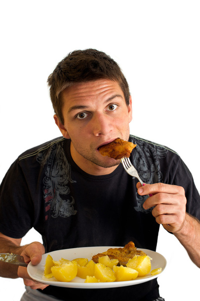 Young man eating a Schnitzel and potatoes - Photo, Image