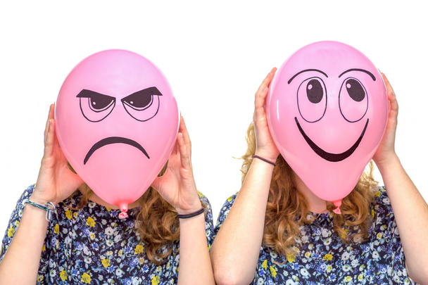 Two girls holding pink balloons with facial expressions - Photo, Image