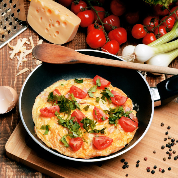 Omelette with ham, tomatoes and chees on the frying pan. - Fotó, kép
