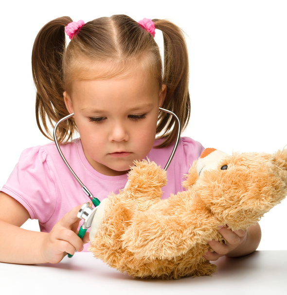 Little girl is playing with her teddy bear - Фото, изображение