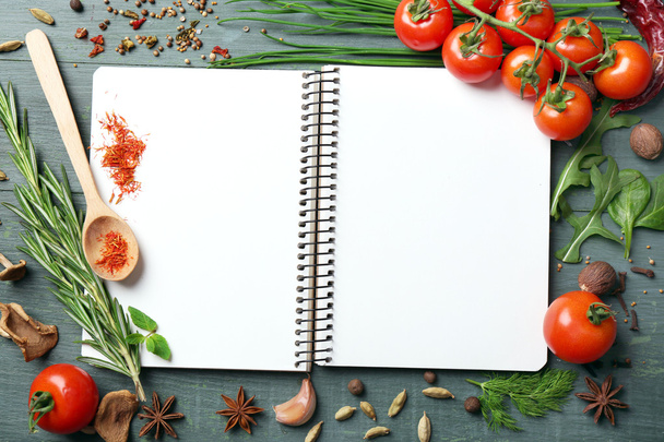 Open recipe book with fresh herbs, tomatoes and spices on wooden background - Zdjęcie, obraz