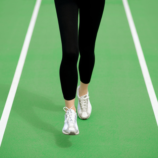 Nainen urheilija juoksija jalat käynnissä Green Running Track. Fitness ja Workout Wellness käsite
. - Valokuva, kuva