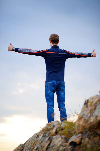 Young Man Standing on Mountain Peak with Arms Raised. Active Lifestyle Concept. - Photo, Image